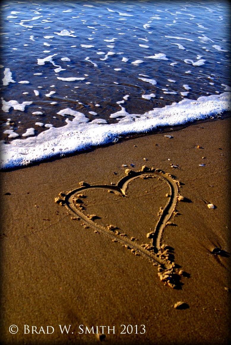 heart drawn in the sand near ocean waves